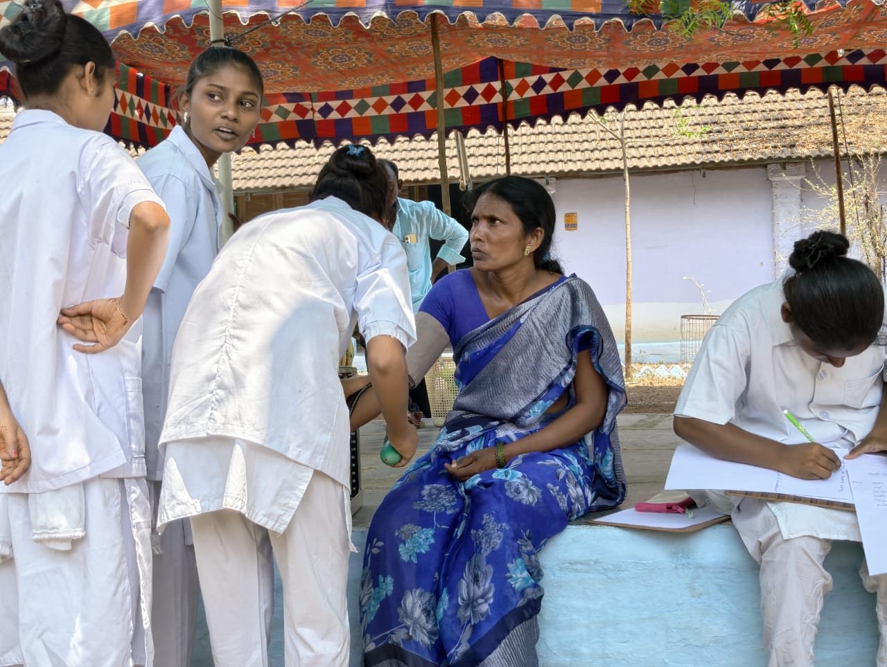 Nursing students supporting a patient during a community medical camp